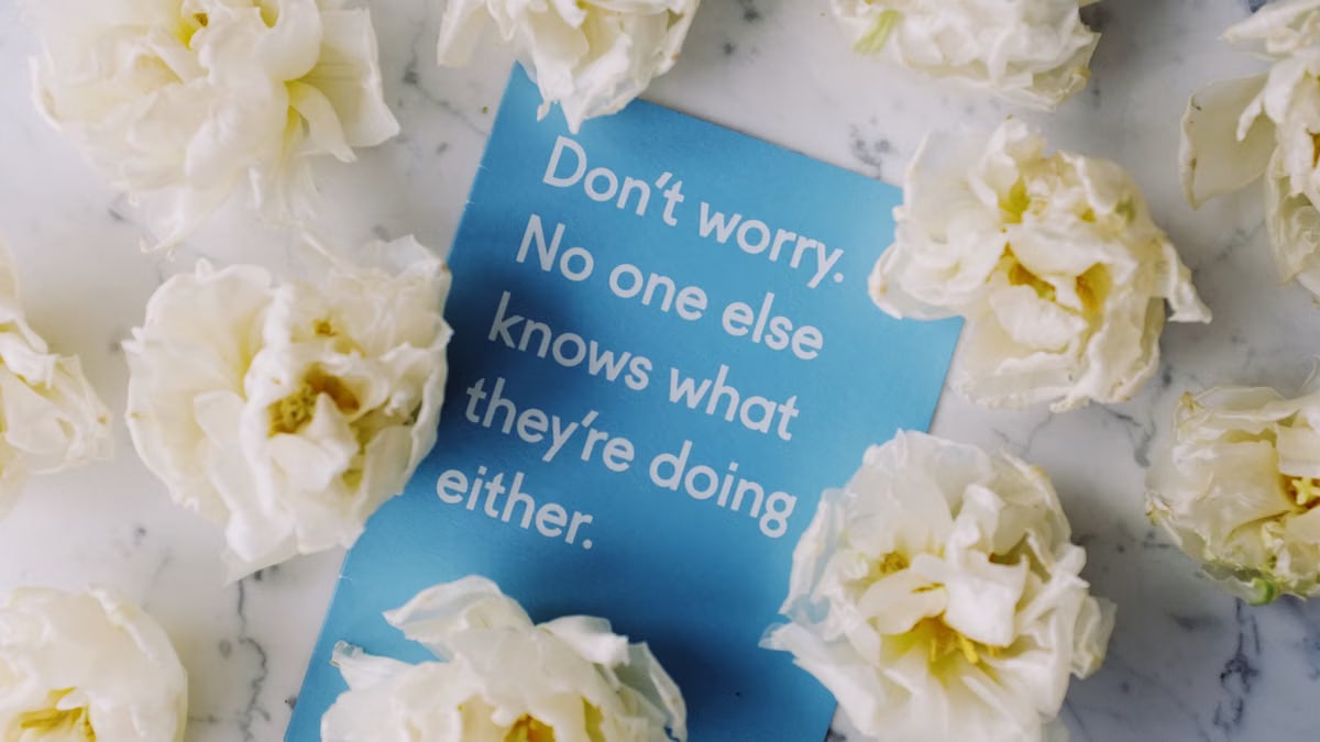 White flowers encircle a motivational card on marble. Perfect for uplifting and positive themes.